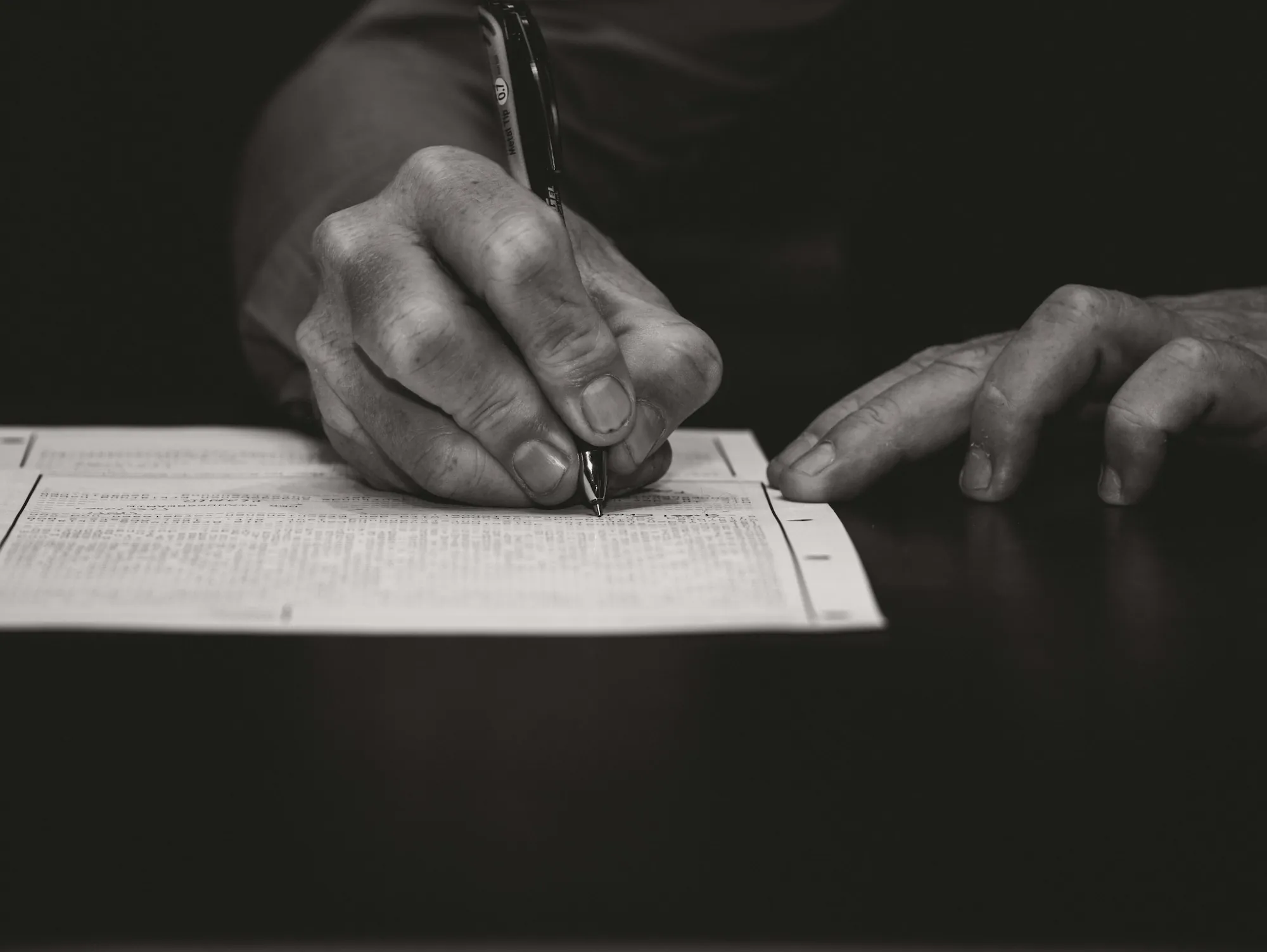 Hands signing a document in black and white